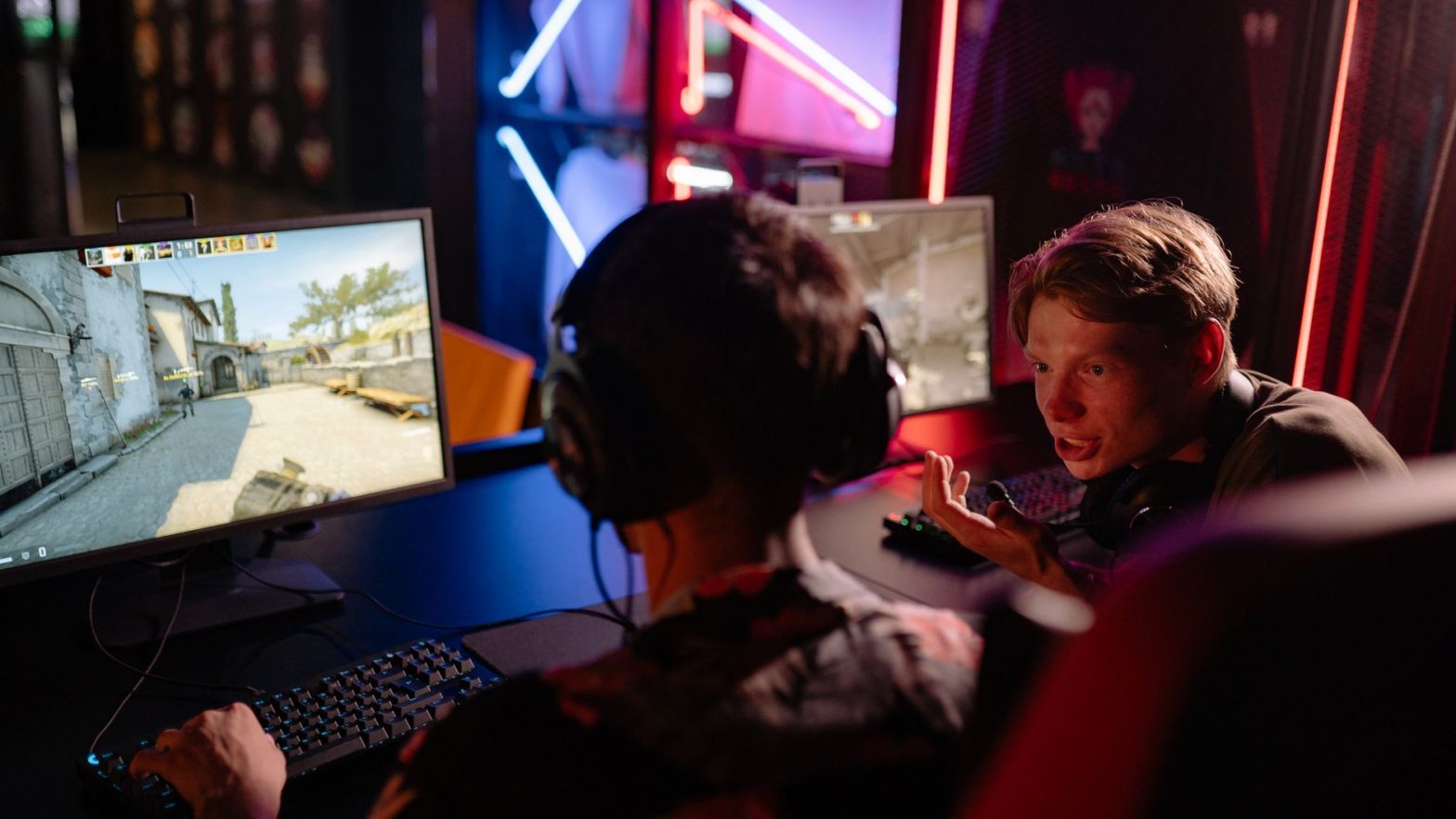 Two gamers engaged in a heated video game session surrounded by neon lights and computer screens. — Betting Sites Ireland Ens
