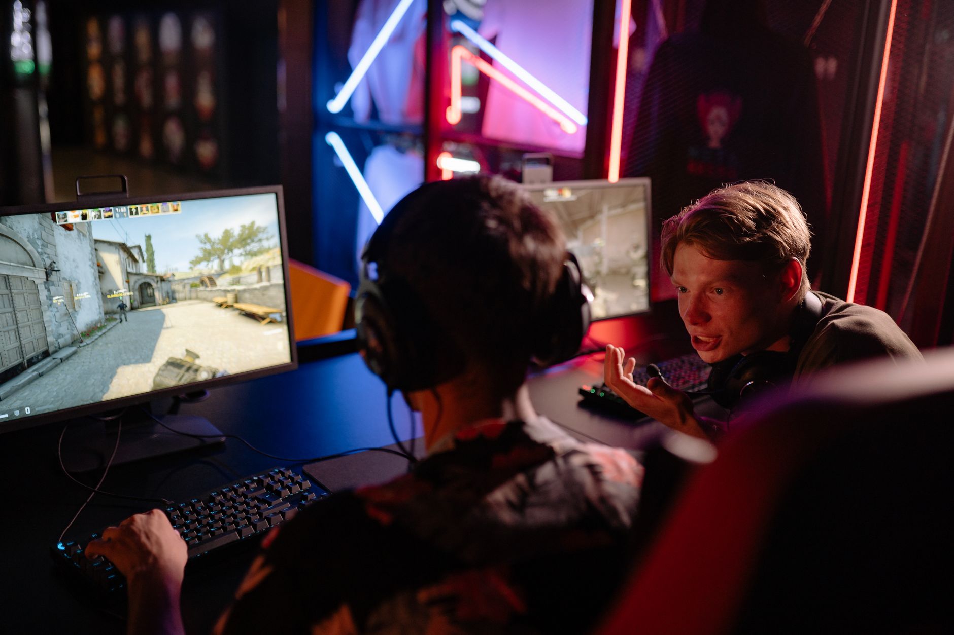 Two gamers engaged in a heated video game session surrounded by neon lights and computer screens. — Betting Sites Ireland Ens